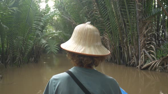 Boat tour in the Mekong River Delta region, Ben Tre, South Vietnam. Tourist with vietnamese hat on c