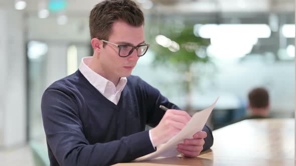 Serious Young Businessman Writing on Paper