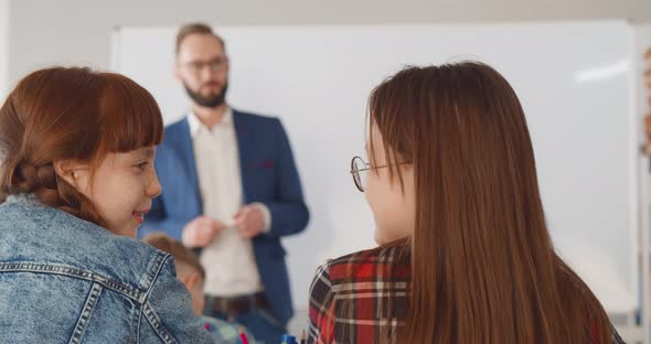 Back View of Preteen Girl Chatting and Laughing During Lesson in Classroom