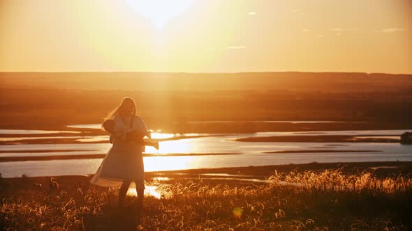 Young Woman Spinning Her Baby While Standing at Nature on Sunset