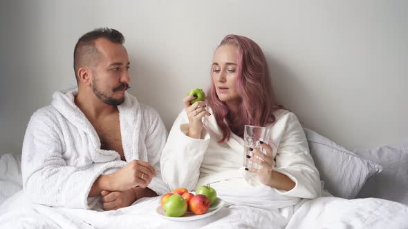 Cheerful Couple Have Breakfast on Bed at Weekend After Waking Up