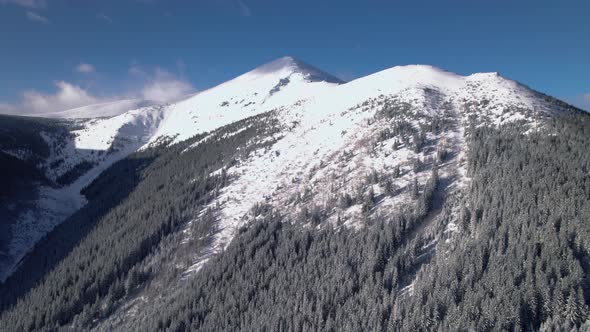 Drone Rising Above Forest Hill Revealing White Mountain Top