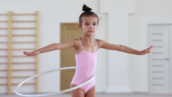 A Little Acrobatic Girl Training with a Hoop in Ballet Studio