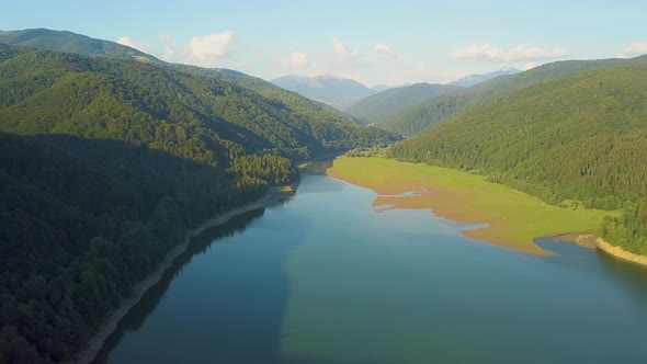 Aerial View of Big Lake with Clear Blue Water Between High Mountain Hills Covered with Dense