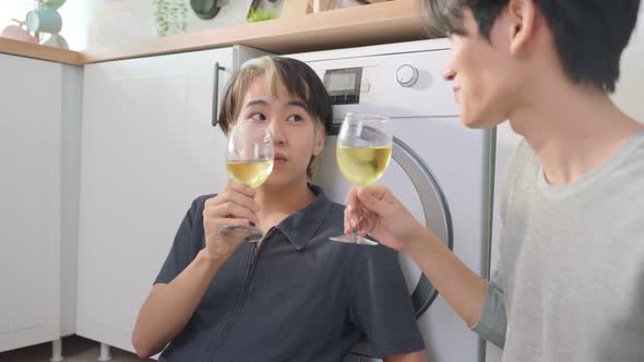 Asian handsome man gay family sit on floor, drink cup of wine together to celebrate anniversary