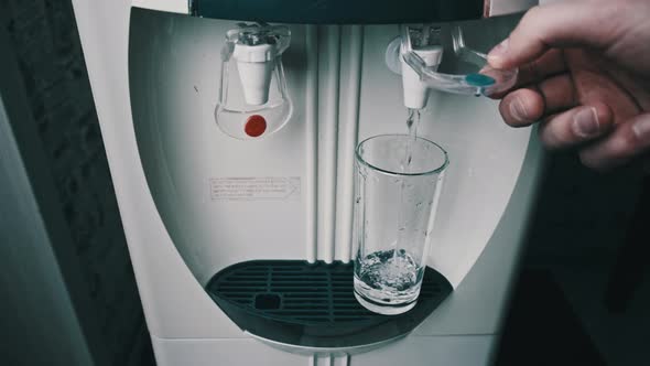 Clear Water is Pouring Into Glass From the Water Cooler