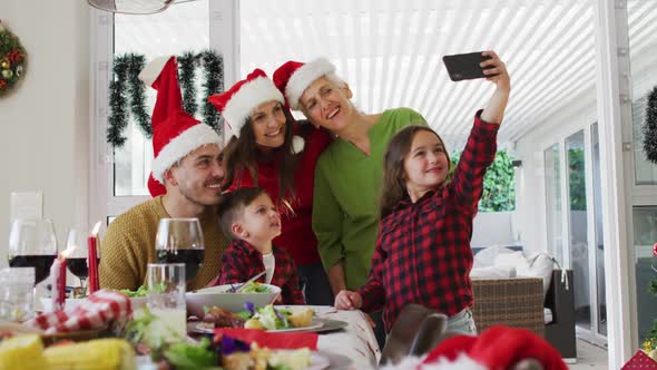 Happy caucasian multi generation family wearing santa hats taking selfie