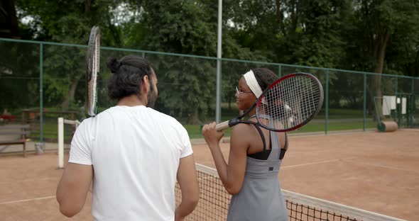 Multi Ethnic Man and Woman in Sportswear Talking About Tennis on Court