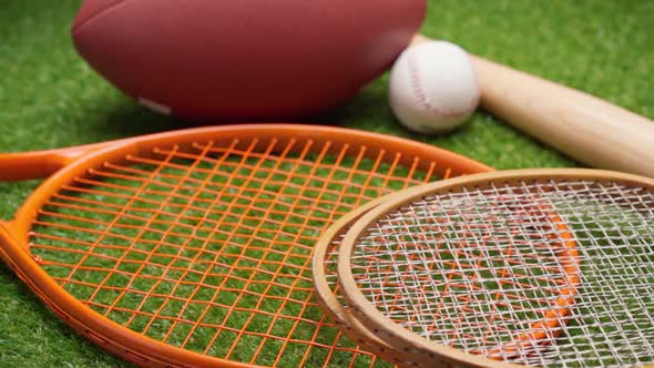Sport Equipment Rackets Balls and Baseball Bat on Grass