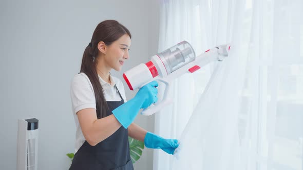 Asian cleaning service woman worker cleaning in living room at home.