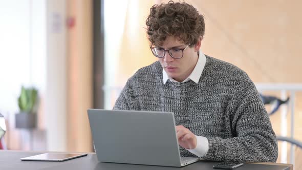 Young Man Reacting to Loss on Laptop at Work
