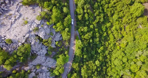 Aerial drone view of a minivan car vehicle driving on a rural road