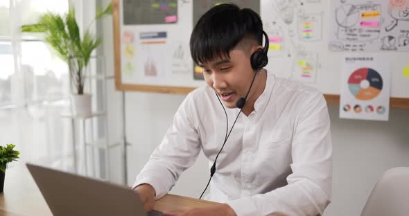 Happy male wears headset video calling on laptop