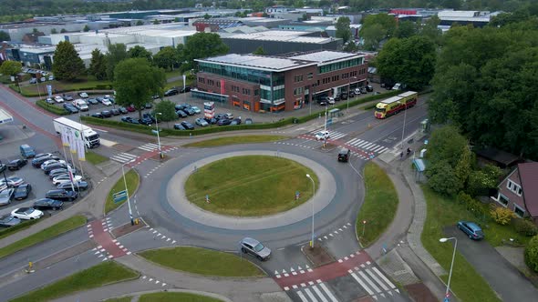 Aerial over busy roundabout and flying over industrial building with solar panels on rooftop