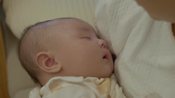 The face of a baby sleeping in the mother's arms. Asian baby.