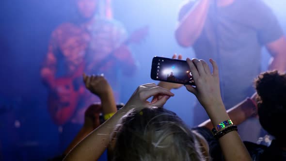 Audience recording video of musical band on mobile phone