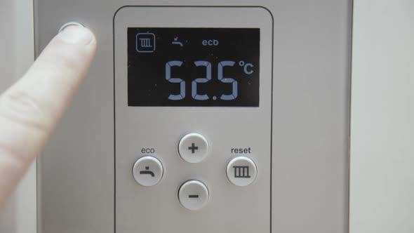 Male Finger Touches Boiler Display for Temperature Control