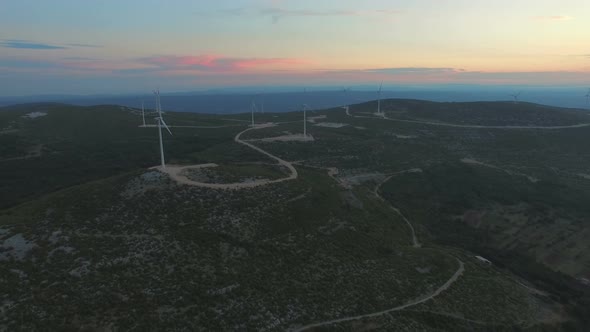 Aerial view of dozen windmills for the production of electric energy, at sunset