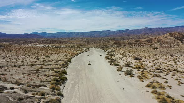 Flying above a dirt road through a colorful but barren desert landscape