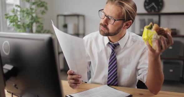 Businessman Reading Documents and Eating Burger