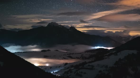 Magic Starry Night Sky with Stars in Winter Alpine Mountains with Foggy Clouds
