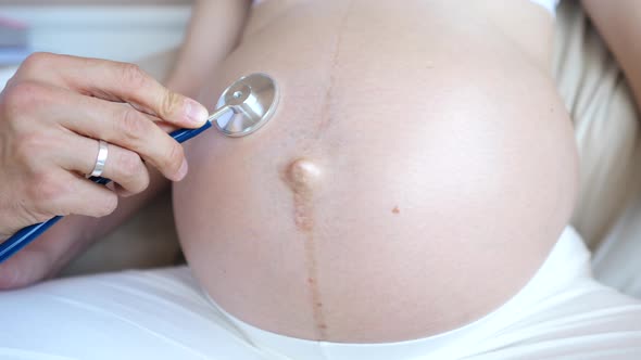 Doctor Using Stethoscope To Hear Belly Of Pregnant Woman