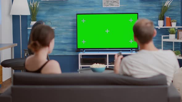 Back View of Man Browsing Tv Channels on Green Screen Looking for Girlfriend Favourite Show