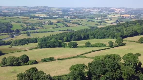 Drone footage of a vast valley of green fields and meadows of a countryside.