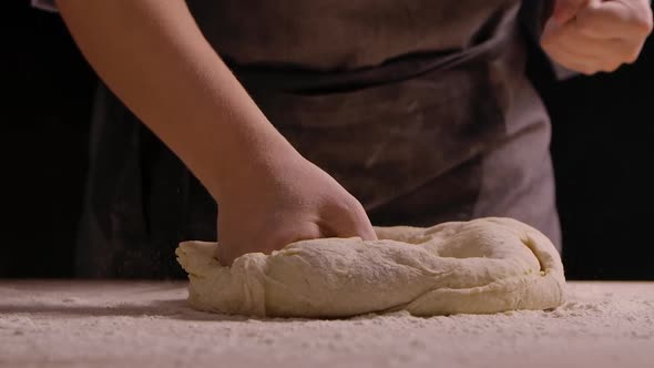 Woman Hands Hit with Fists Kneading Dough in Flour on the Table