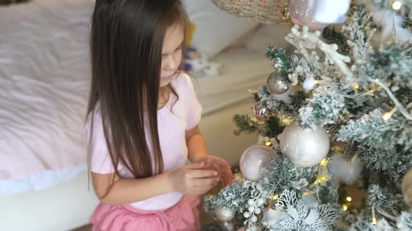 Adorable Little Girl Decorating a Christmas Tree at Home