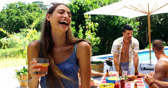 Happy woman looking at friends behind while having cocktail drink