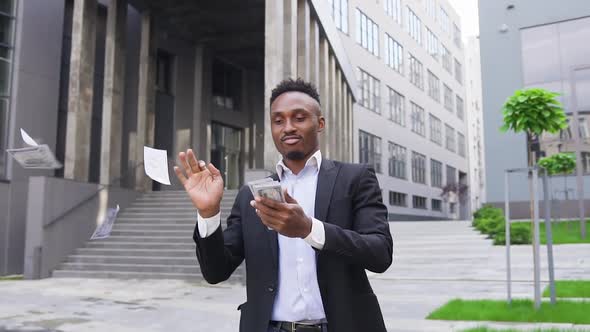 African American which Scattering Money in Front of Modern City Building Simultaneously Dancing