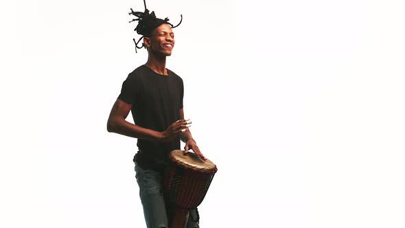 Black Smile Man Plays the African Drum with His Hands in the Studio