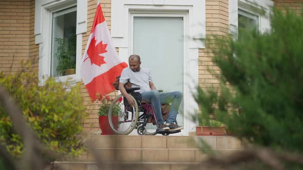 Wide Shot Portrait of Adult African American Man in Wheelchair Thinking Sitting on Porch with