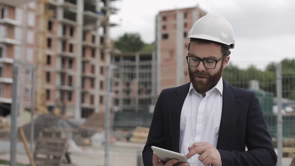 Architect Man Wearing Business Suit Walking with Tablet on the Construction Site and Analyzing