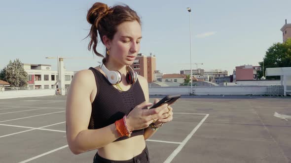 Slow motion shot of young woman using smartphone on parking deck