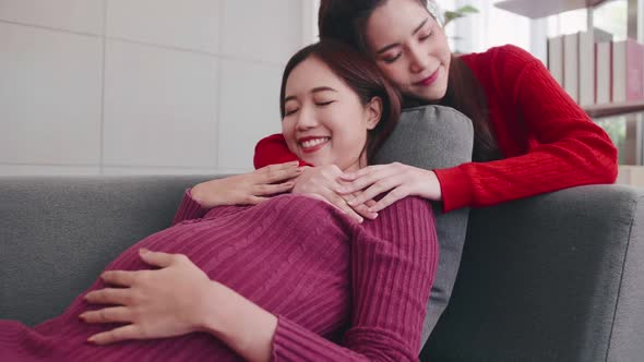 Pregnant Asian lesbian woman and her partner are happy to spend time together at home.