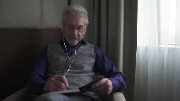 Portrait of an Gray Haired Designer with Glasses Working on a Project and Writing Down Thoughts in a