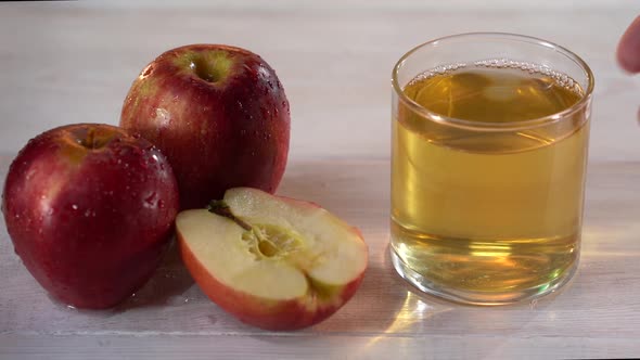 Man's Hand Put the Glass with Apple Juice on the White Table