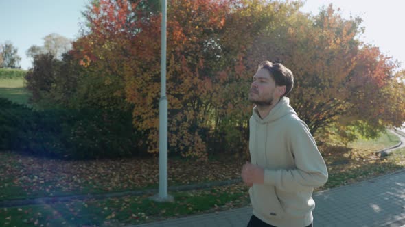 Man Running on Jogging Track at the City Park in Sunny Autumn Morning