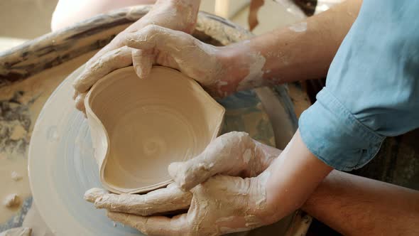 Close-up of Man and Woman's Hands Making Ceramic Bowl in Shape of Heart in Workshop