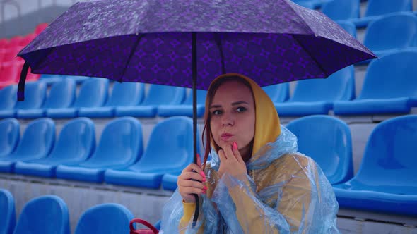 Pensive Lady with Umbrella Touching Chin and Looking Away on Tribune