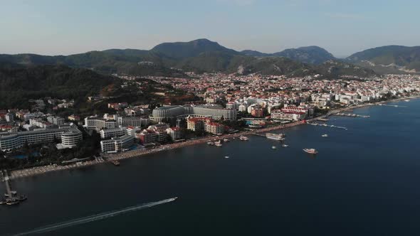 The Boat Sails Along the City Beach. Aerial View