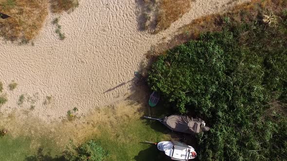 Beautiful coast views with vegetation and fine sands. A rack of surf boards is seen and also some bu