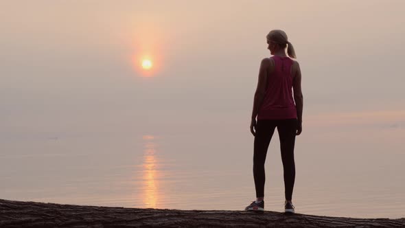 Confident Fitness Woman Looking at Dawn Over the Sea, Rear View