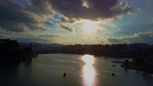 Camera Flies Over Large Lake with Catamarans Against Sunset