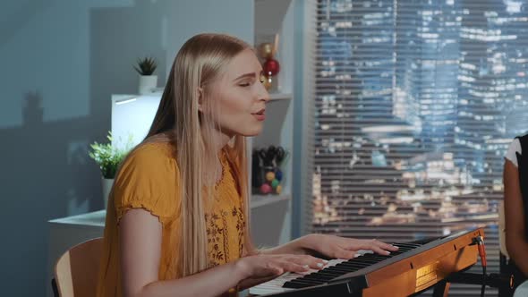 Vocalist Blonde Singing a Song and Playing the Keyboard During Rehearsal of Her Band in Home