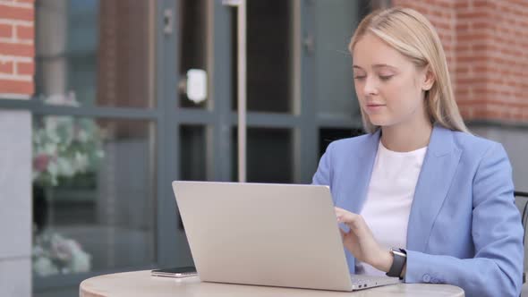 Young Businesswoman Celebrating on Laptop Sitting Outside Office