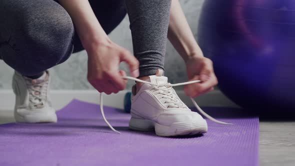 A Woman Ties Shoelaces on Sneakers