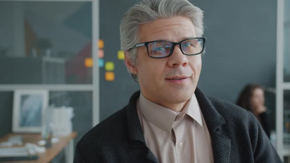 Slow Motion Portrait of Good-looking Mature Man in Glasses Smiling in Office